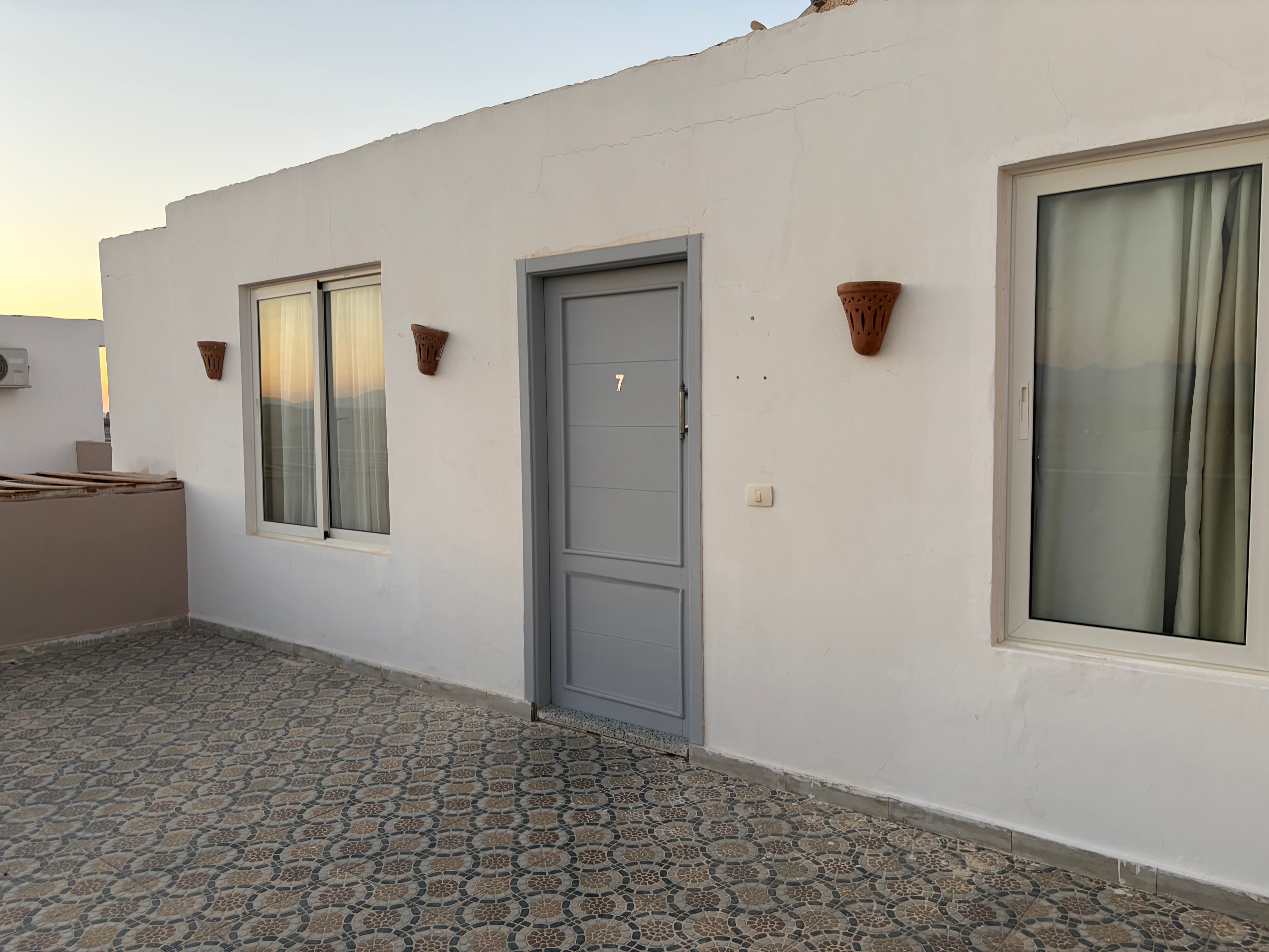 Unauthorised rooftop villa unit — windows, sliding door and wall lights built under the mosaic ceiling of the former relaxation zone