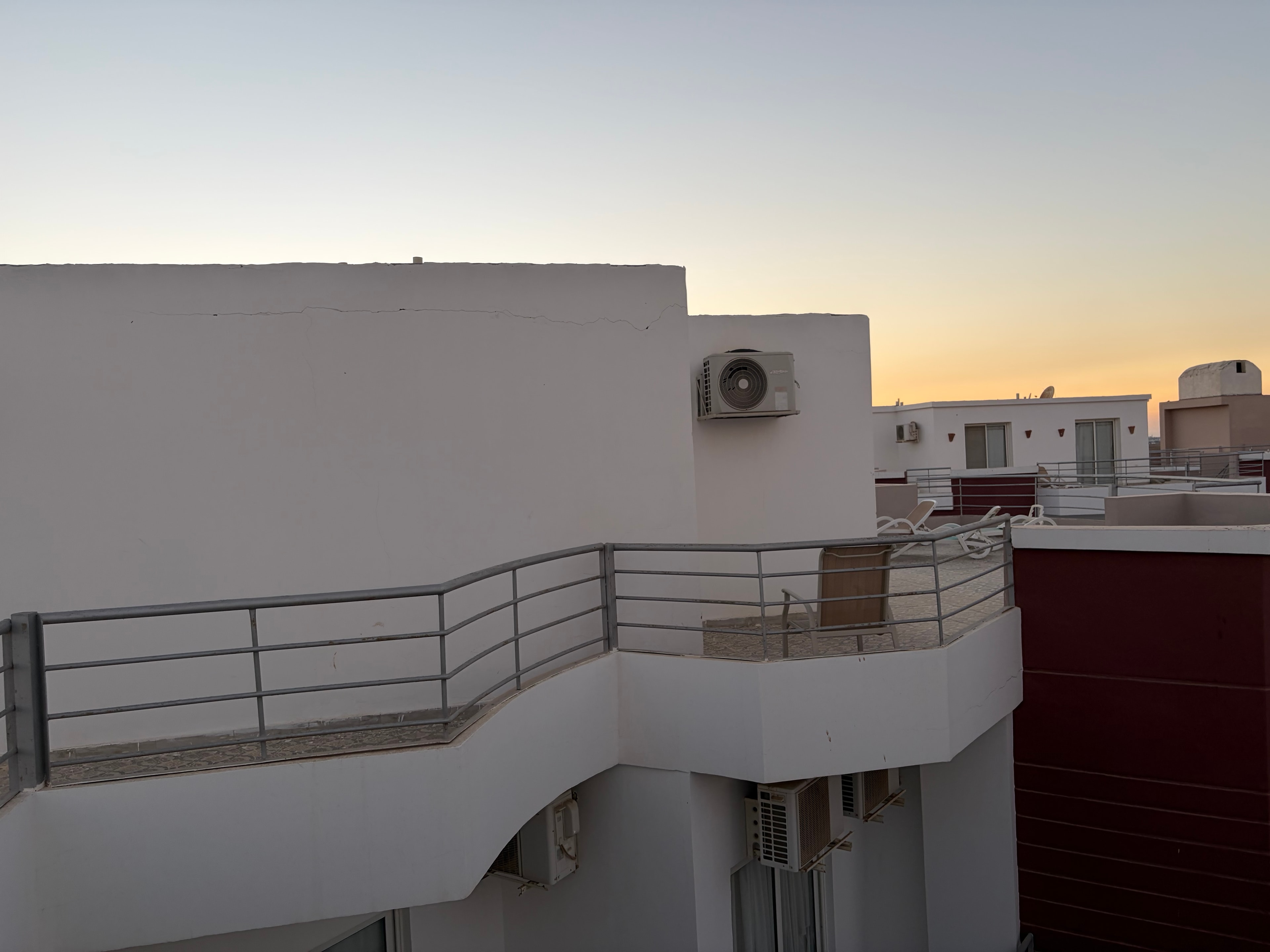 External view of illegal rooftop villa constructions — multiple AC units, metal balustrades, structures built on top of the resort building