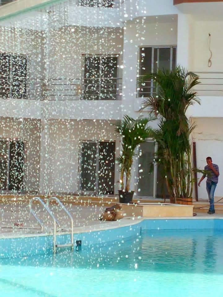 Photograph of the waterfall curtain feature in operation — crystal clear blue pool, tropical palms, the feature that no longer exists