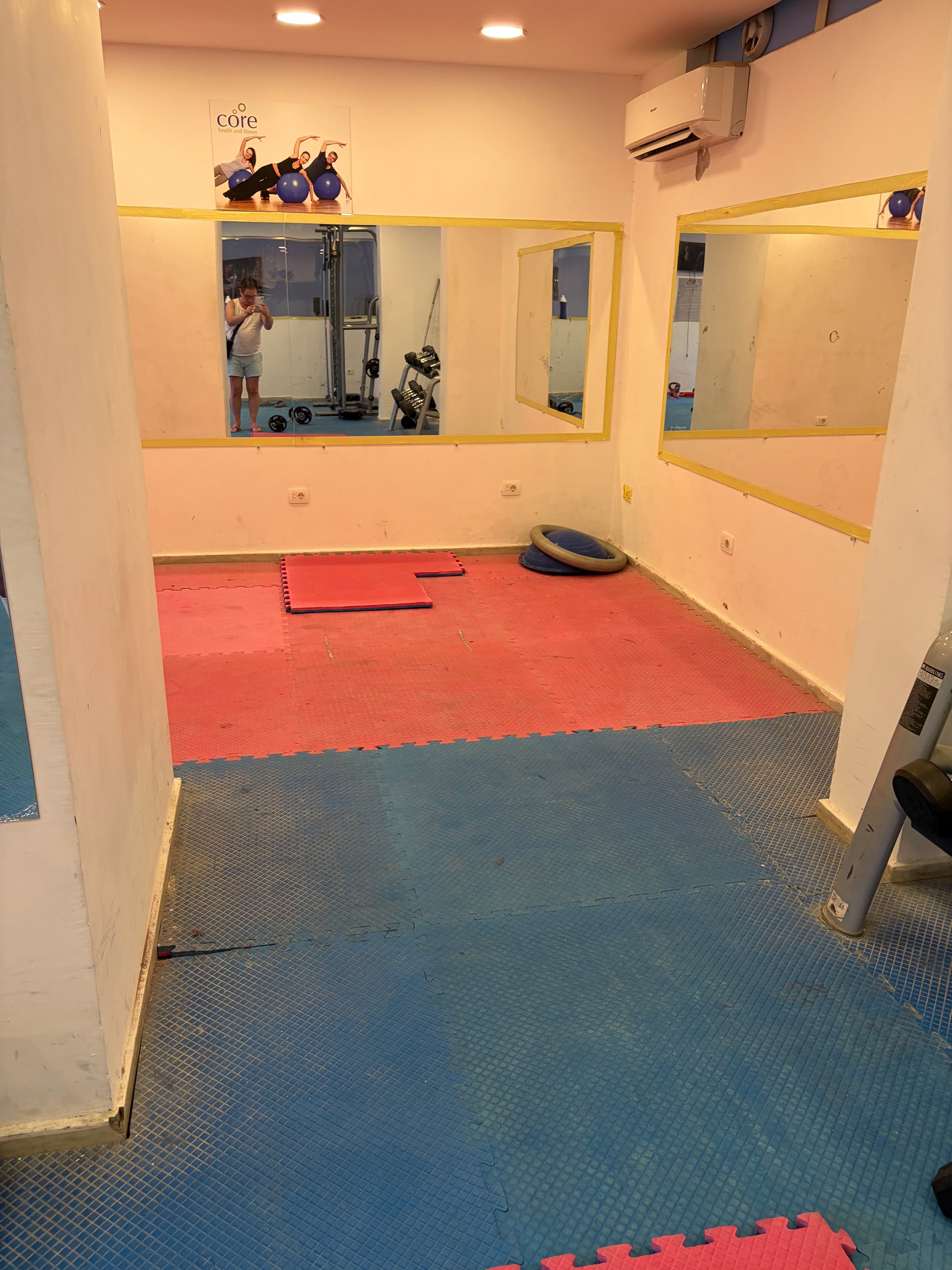 Gym rules notice taped to bare pillar next to wall-mounted TV