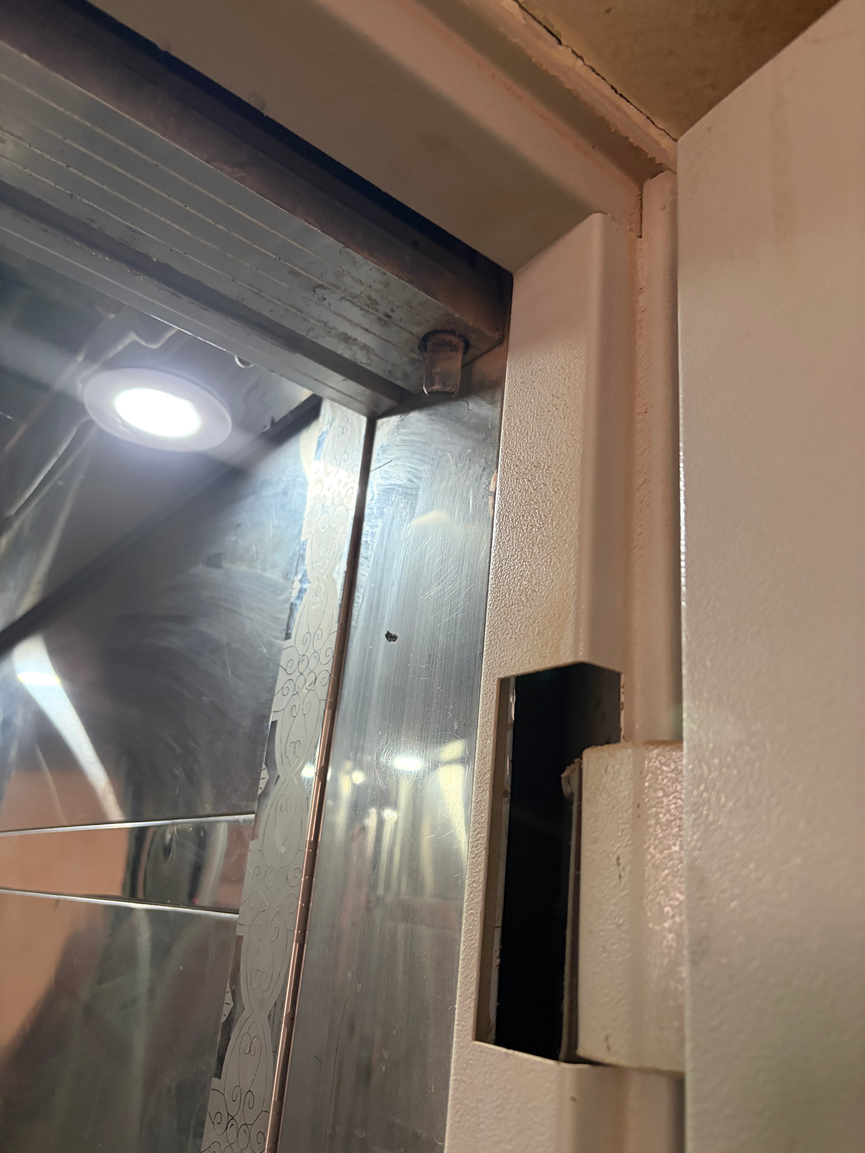 Top corner gap — large black void where door meets frame, shaft completely open, rusted bolt visible