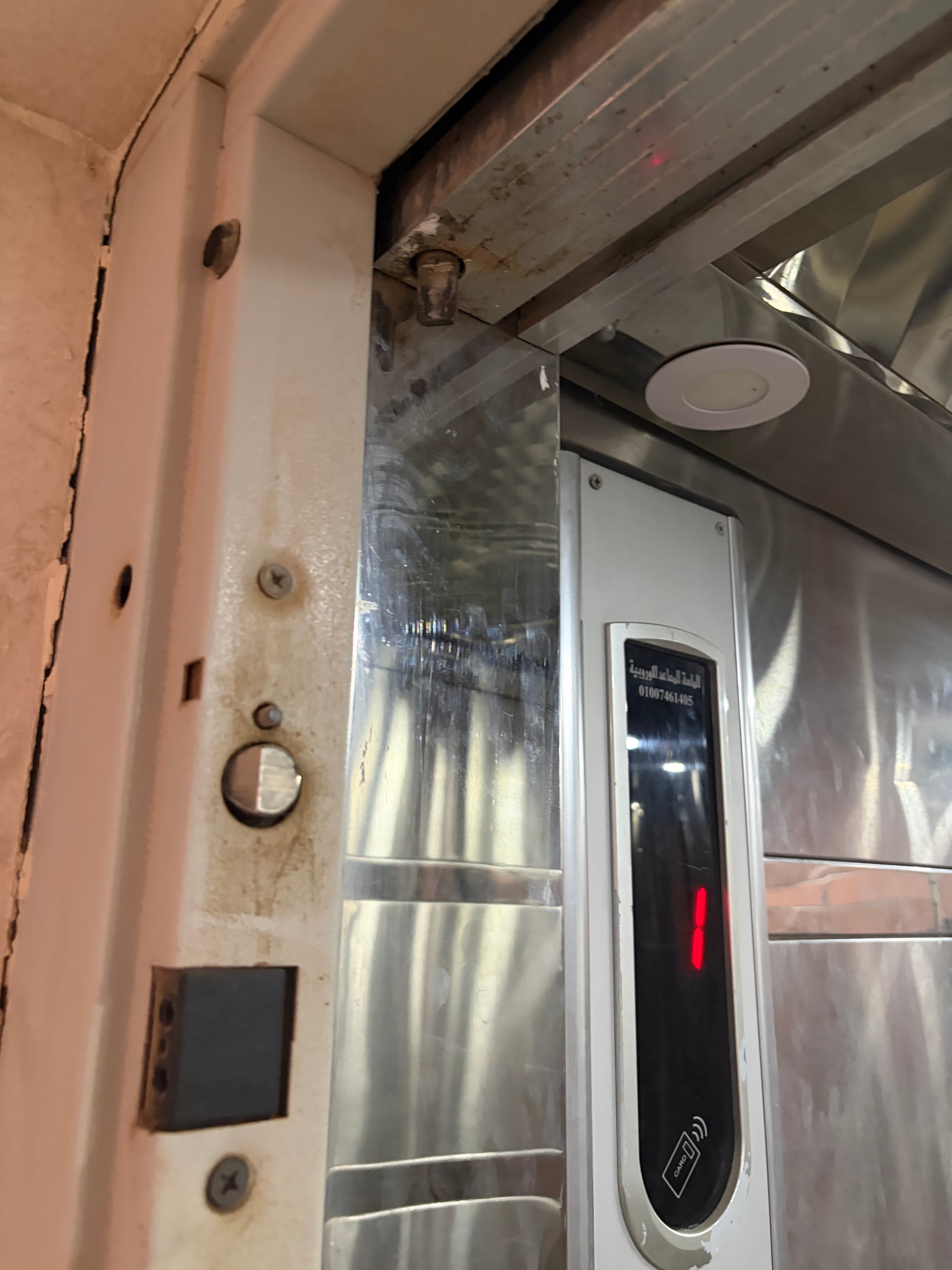 Error display panel showing red fault code — door gap and shaft visible below, cracked concrete at threshold