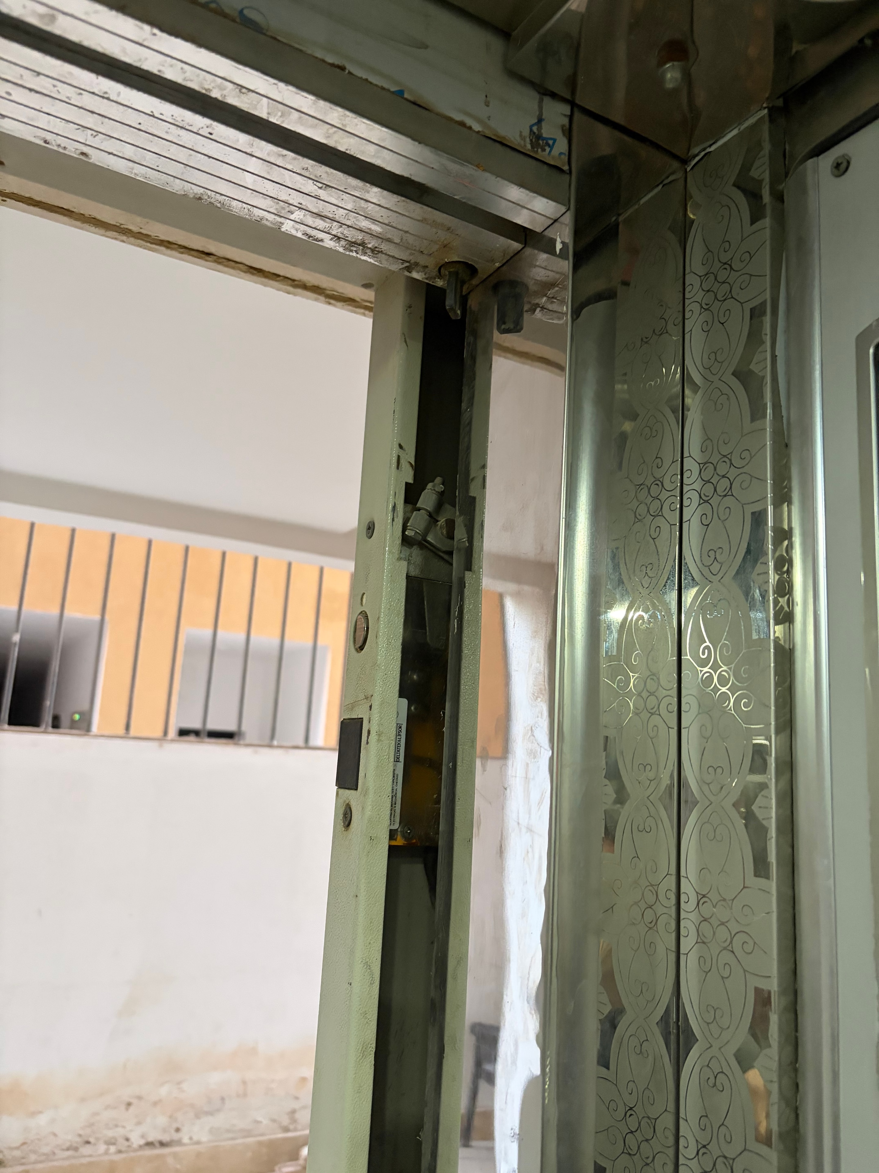 Lift door track and drive mechanism fully exposed — dirty corroded components, shaft gap open behind