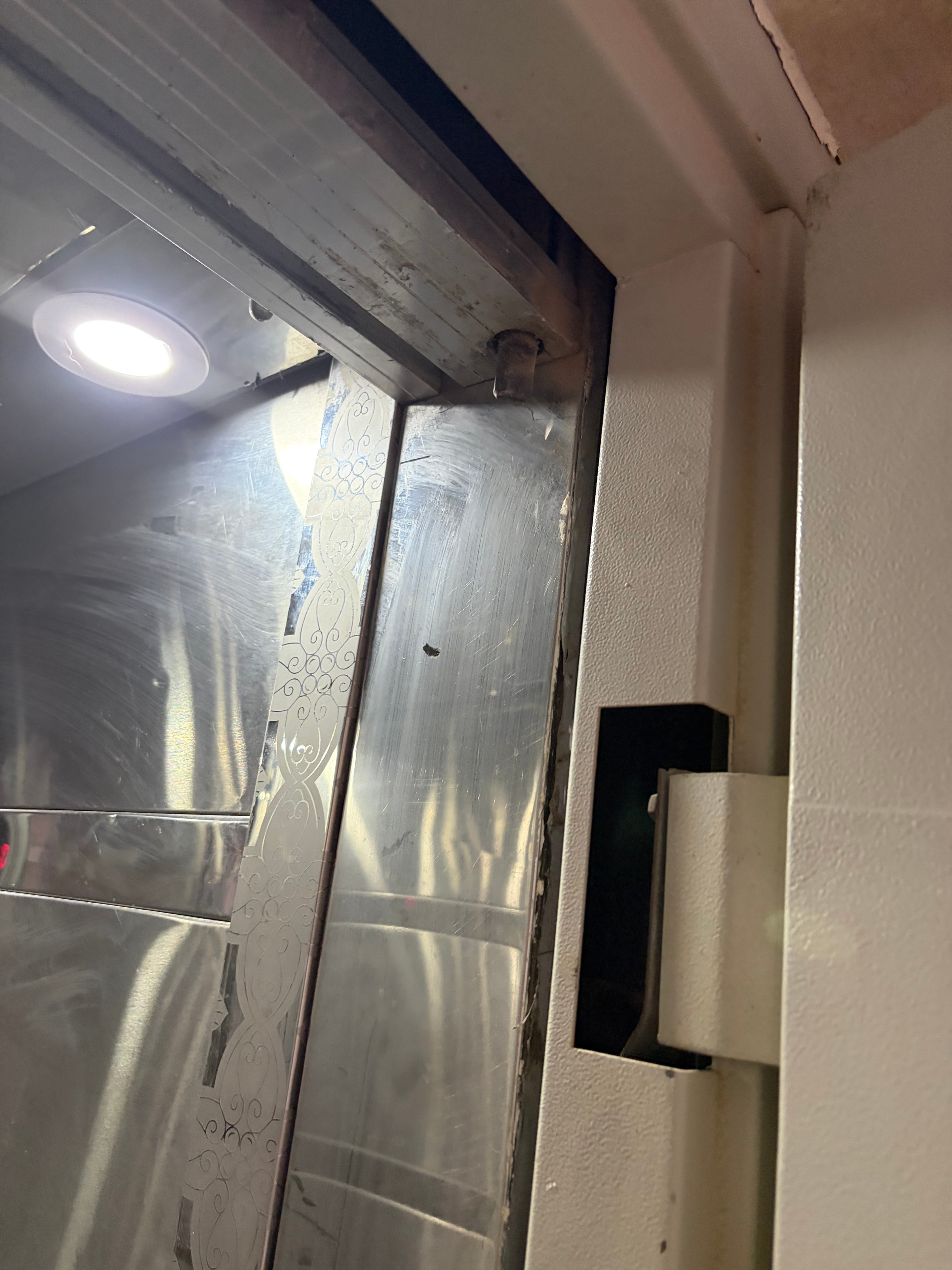 Looking down into open lift shaft — black sensor housing with no sensor fitted, scratched panels
