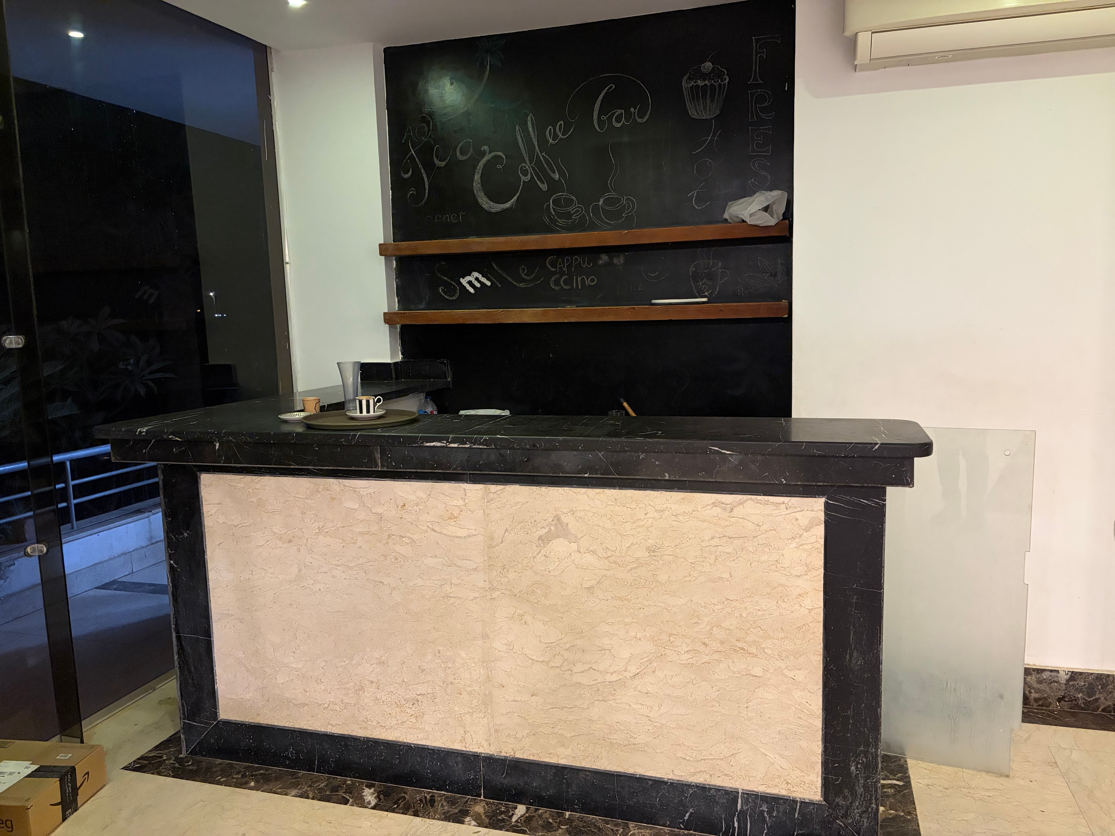 Lobby bar counter covered in debris — broken cabinet stuffed with rubbish, empty cans, plastic bags and bottles across the bar surface