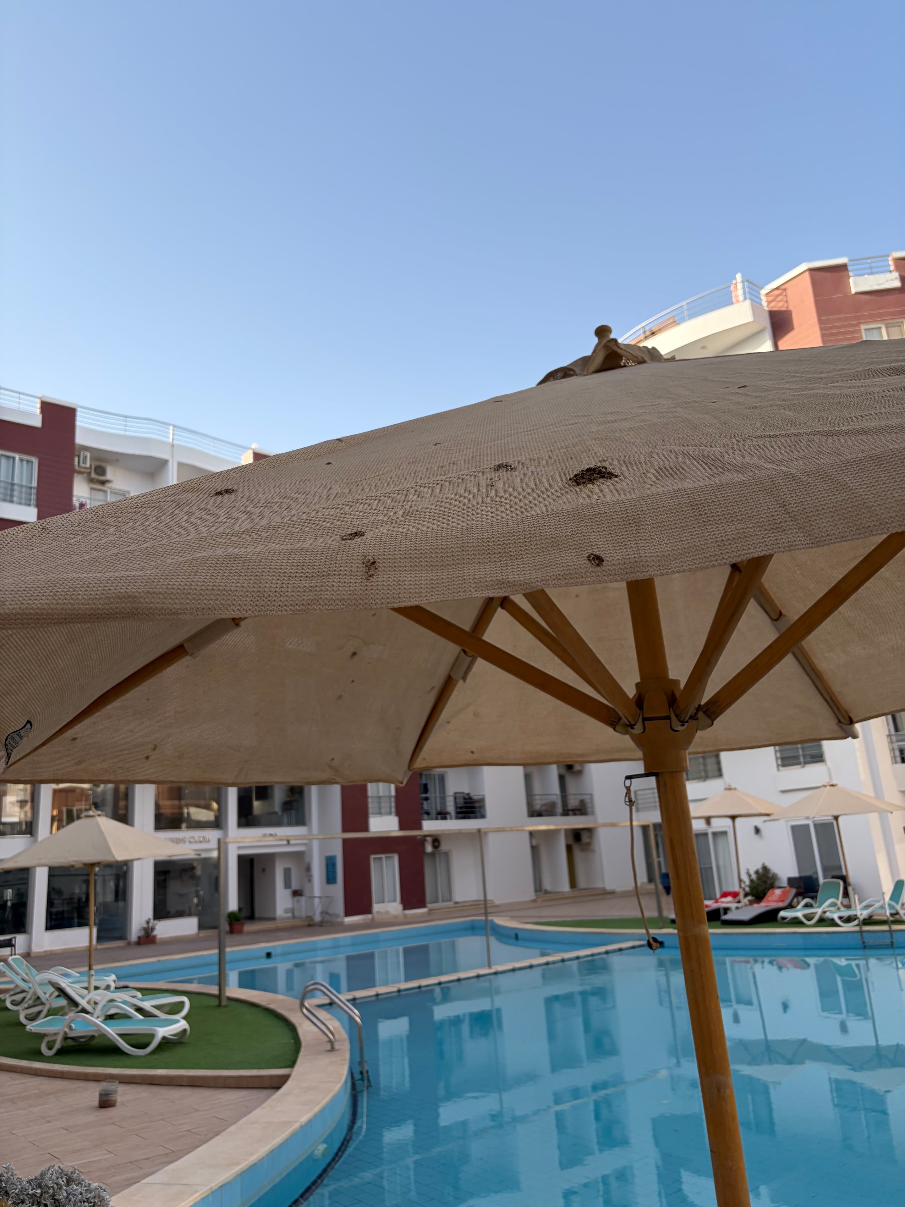 Sun lounger frame close-up — white plastic heavily soiled and stained, mismatched replacement tiles visible behind