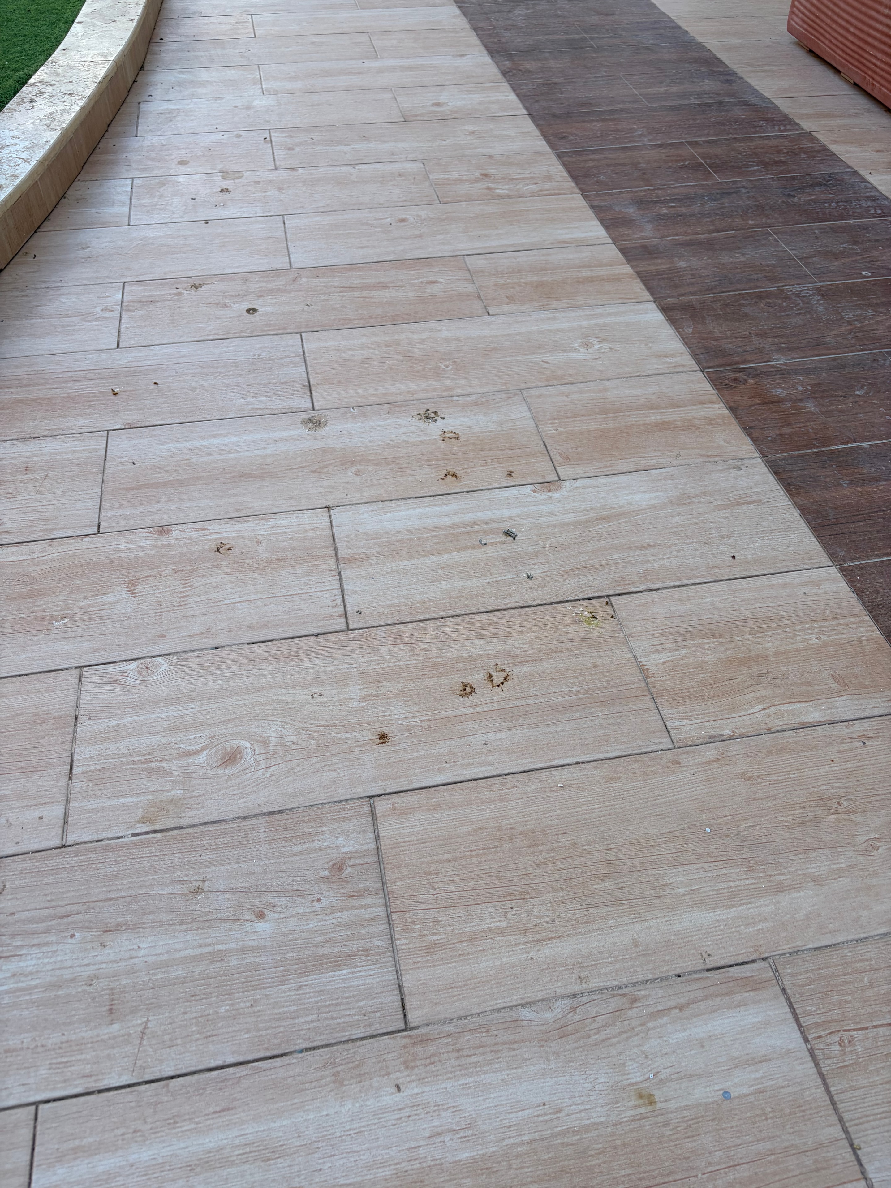 Mismatched floor tiles with faecal handprint pressed onto dark replacement tiles — botched repair work clearly visible alongside contamination
