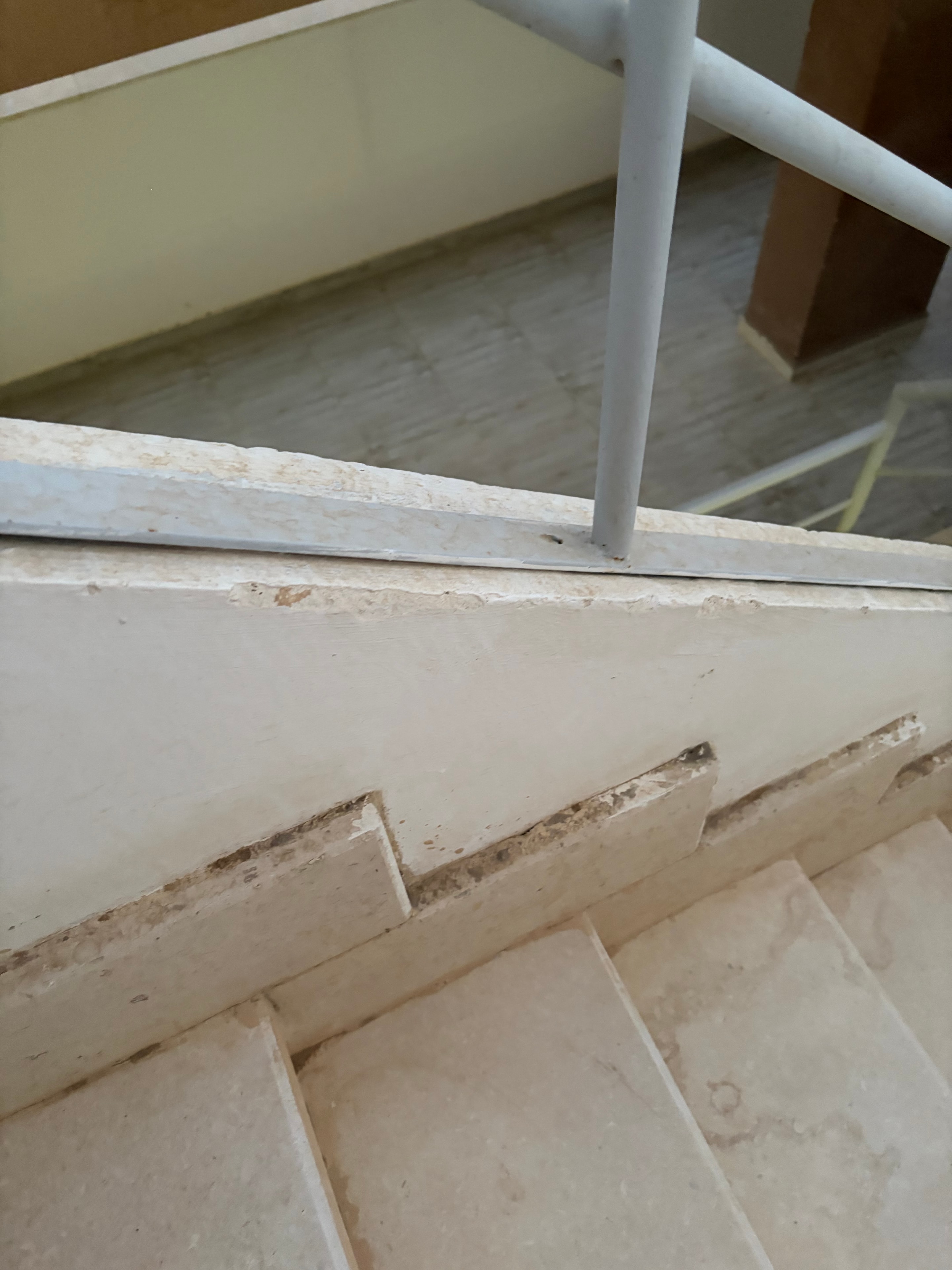 Mattress balanced on top of a metal balustrade railing above a communal atrium — directly above where people walk, a serious safety hazard